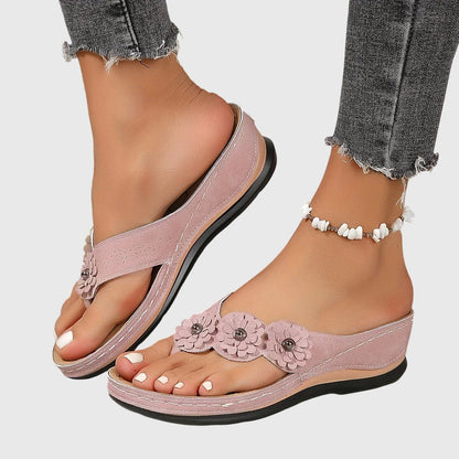 Vrouw ontspant met roze Alexis™ orthopedische teenslippers aan de voeten in een natuurlijke setting