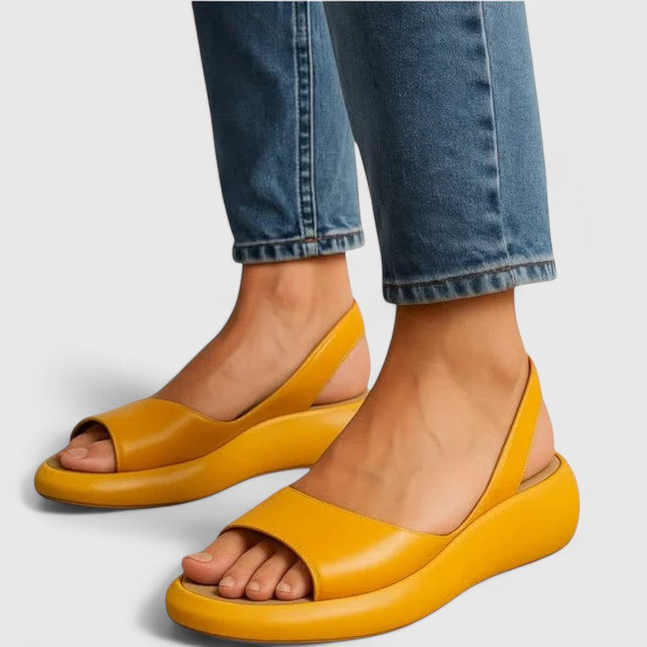 Een vrouw in zomerkleding met witte Emrynn sandalen, loopt ontspannen en elegant.