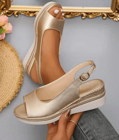 Model draagt gouden Ange sandalen in close-up, met focus op de bandjes en zool.