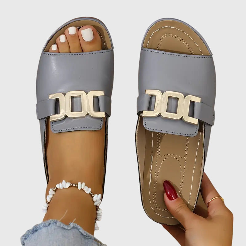 Twee Kathryn™ gespsandalen in verschillende kleuren (beige en wit) naast elkaar op een effen achtergrond